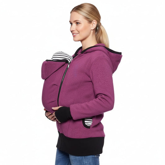 Woman wearing the plum kangaroo babywearing jacket with a baby tucked into the front carrier pouch