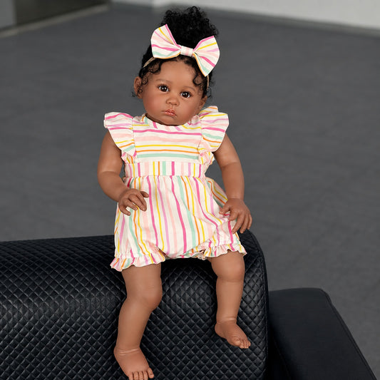 60cm reborn baby doll sitting on a dark ottoman, close-up of face and curly hair