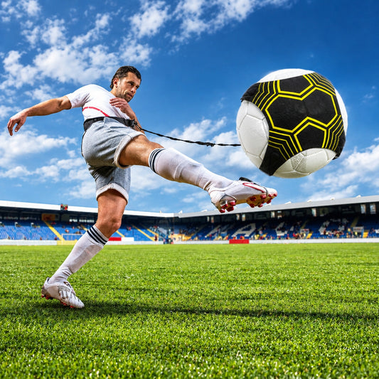 Child practicing solo soccer kicks on a stadium field using the training belt with elastic cord attached to the ball