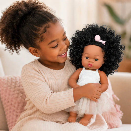 Girl holding curly hair baby doll wearing white ballet outfit