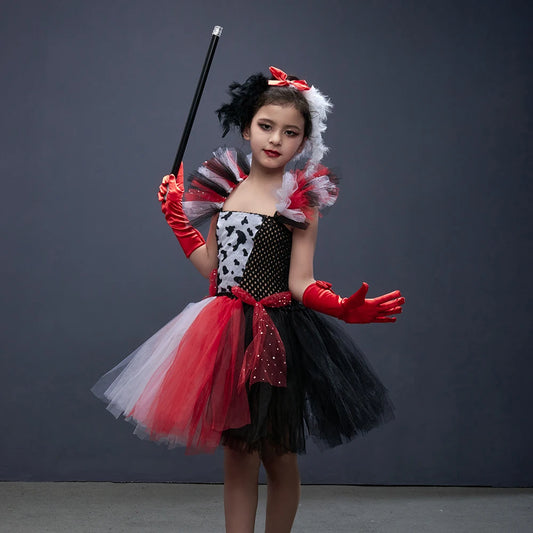 Girl wearing dalmatian-spot villain tutu dress costume with feathered headband, red gloves and prop cane