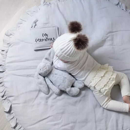 Grey round ruffled baby play mat with baby crawling