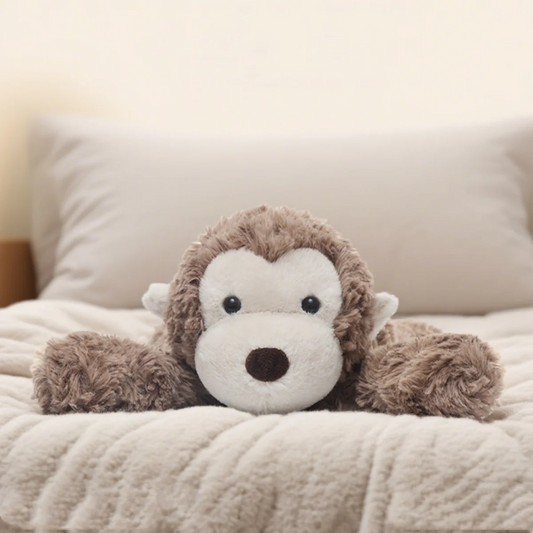Soft plush monkey toy lying on a bed pillow
