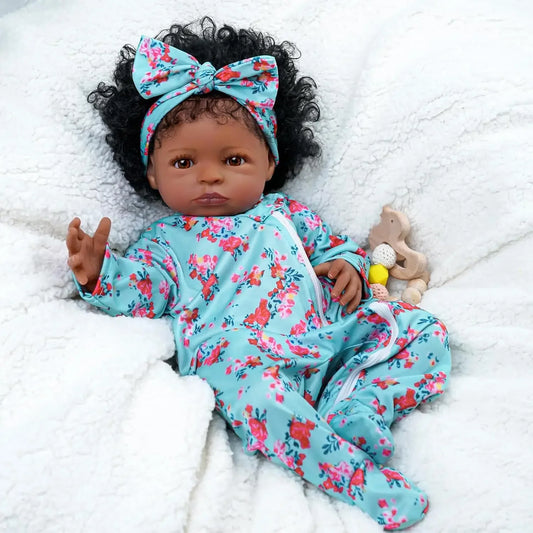 Reborn baby doll lying on blanket in teal floral outfit