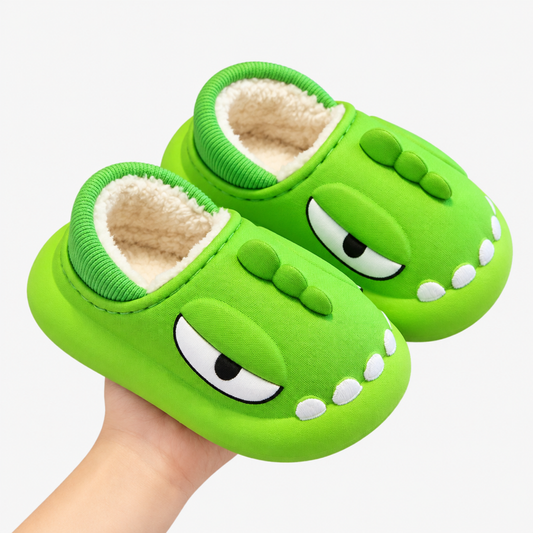 Light green dinosaur-face cotton slipper held in hand, white studio background