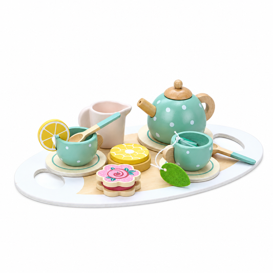 Close-up of wooden play tea set with biscuit, cake slice and lemon slice accessories beside teapot and cups