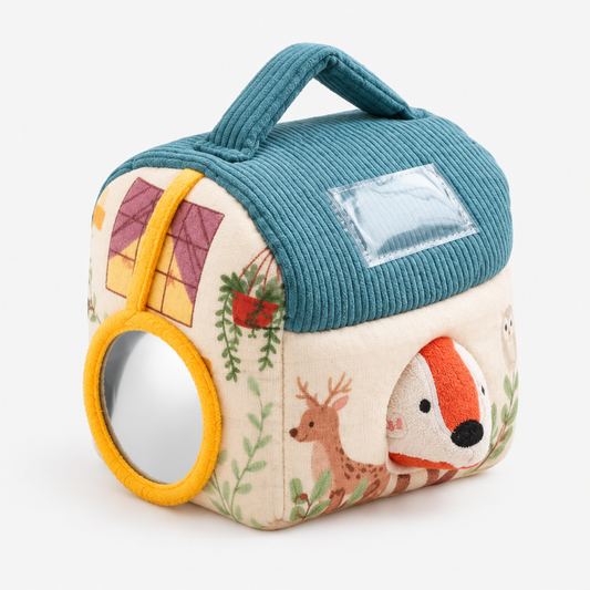 Angled view of the plush farm animal sensory barn toy showing the teal corduroy roof, yellow ring handle, and round mirror window on a clean white background