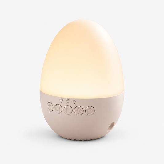 Egg-shaped baby white noise machine and night light at a three-quarter angle, showing the glowing dome and control panel, white studio background